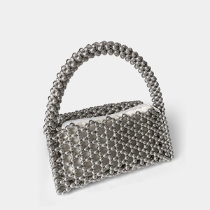 Detail of silver beaded handbag showing textured metallic beads and white zipper lining