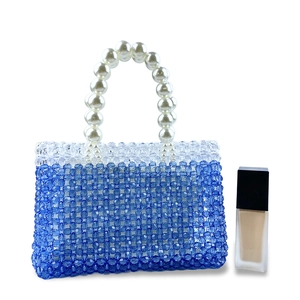 Detail of blue beaded handbag with pearl handle and size reference cosmetics