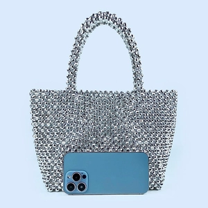 Silver beaded tote bag detail with smartphone for size reference on light blue background