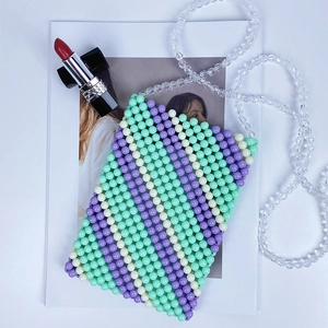 Detail of handmade beaded crossbody bag with mint green stripes and crystal strap