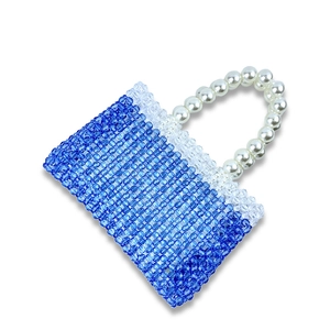 Detailed close-up of handmade blue gradient beads and elegant pearl handle on a handbag