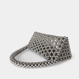 Macro detail of silver triangular hollow metal beaded bag with woven honeycomb texture