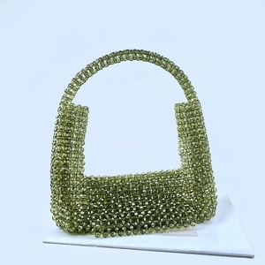 Detail einer grünen handgefertigten Perlenhandtasche mit feinem Hohlgeflecht und Griff