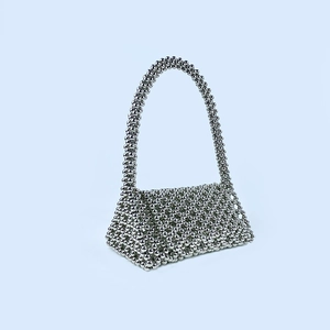 Détail du sac à main en perles argentées avec tissage évidé et longue poignée chic