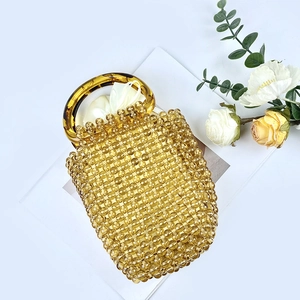 Dettaglio borsa a secchiello in perline acriliche color ambra con fodera in raso e manici tondi