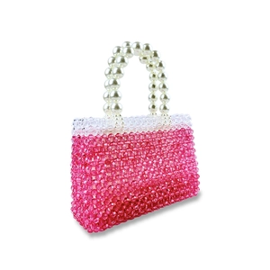 Macro detail of handmade pink beaded square handbag with white pearl handle on white background