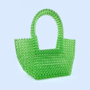 Detail of green acrylic beaded tote bag showing hand-woven texture and curved handles
