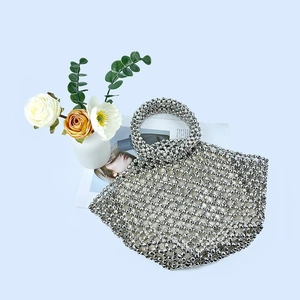 Detailed view of silver beaded basket bag with ring handle on a blue background