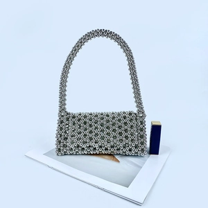 Détail du sac à main perlé argenté montrant la texture tissée et la longue poignée