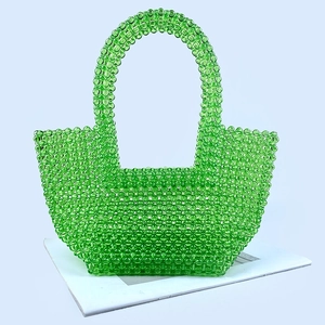 Close-up of a handmade green acrylic beaded tote bag with a woven texture finish