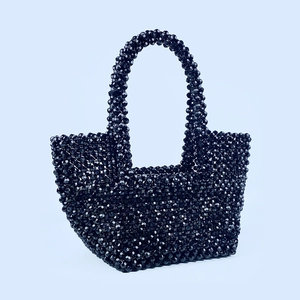 Close-up of hand-woven black beaded tote bag showing faceted bead texture and gloss