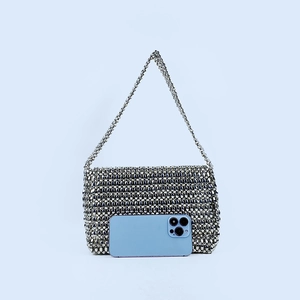Detail view of a silver metallic beaded crossbody bag next to a smartphone for size reference