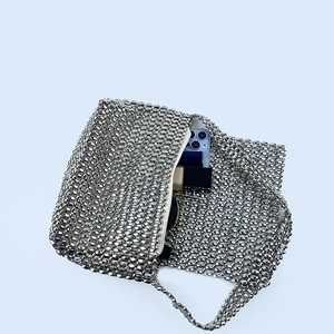 Detail view of silver metal beaded shoulder bag showing interior capacity for phone and makeup