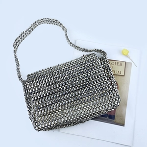Macro detail of silver beaded flap bag with metallic woven texture and slim strap