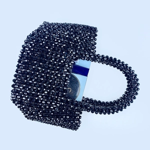 Macro view of black beaded handbag showing internal space for phone and makeup