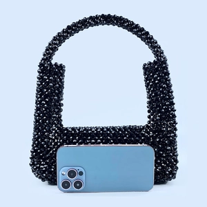 Detail einer handgefertigten schwarzen Perlenhandtasche mit gewebter Textur und Griff