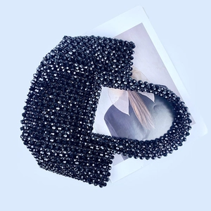 Flat lay of a handcrafted black beaded handbag with a glossy finish on a fashion magazine