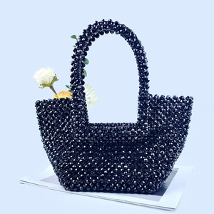 Close-up of black beaded handbag featuring white rose and handcrafted weave texture