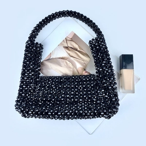 Flachbild einer schwarzen Perlen-Handtasche mit langem Griff und Vintage-Hohlwebmuster