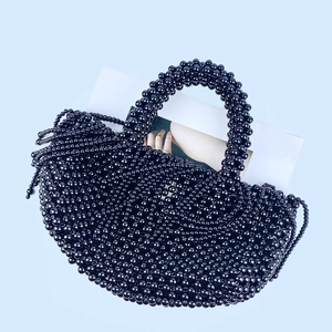 Détail du sac seau noir tissé à la main avec perles, glands à franges et finition polie