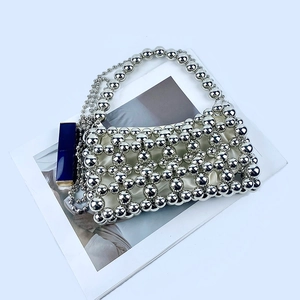 Détail du sac à main en perles argentées avec motif en résille et rouge à lèvres bleu