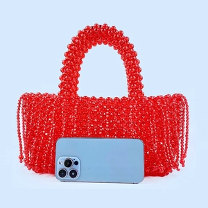 Vue détaillée du sac en perles acryliques rouges avec pompons et détails tissés