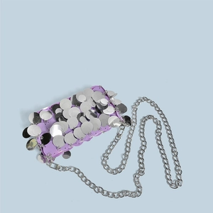 Detail view of light purple sequins and silver metal chain strap on woven handbag