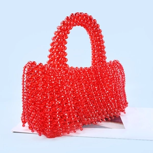 Détails d'un sac à main rouge en perles artisanales avec motifs floraux et pompon