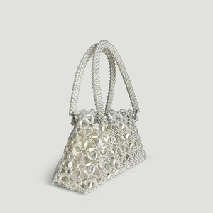 Macro view of handmade white beaded tote bag featuring intricate floral woven texture