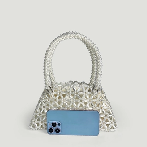 Detail of handmade beaded tote bag showing pearl texture and floral pattern with phone