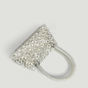 Macro shot of white handmade beaded tote bag featuring intricate floral hollow patterns