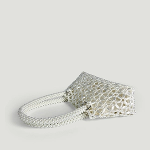 Close-up of handmade white pearl woven handbag with elegant floral geometric patterns