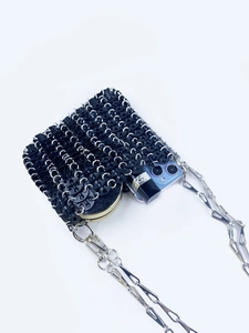 Detail of black metal ring mesh mini bag showing phone and lipstick storage