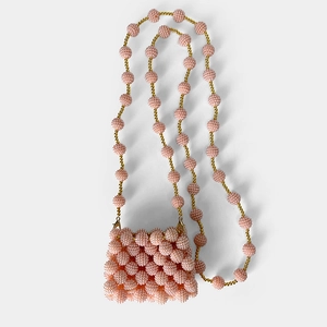 Detailed close-up of handmade pink beaded mini bag with textured pearls and gold clasp