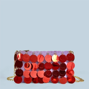 Close-up of layered red sequins and gold chain strap on a shimmering evening clutch bag