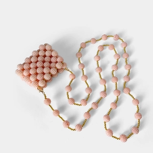 Detailed view of pink beaded mini bag with textured weaving and golden metal clasps