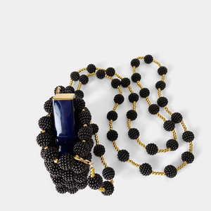 Detail of handmade black beaded mini lipstick bag with golden chain and bead accents