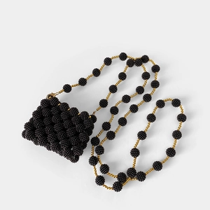 Macro shot of black beaded mini crossbody bag featuring golden chain strap and woven texture