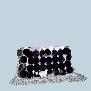 Detailed close-up of a purple sequined evening bag with a silver chain strap and black paillettes