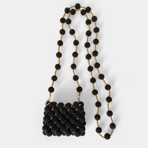 Macro detail of handmade black beaded mini bag showing gold accents and woven texture