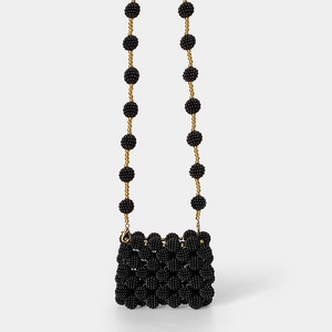 Detail of handcrafted mini beaded bag with black texture and golden pearl accents
