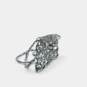 Detail of silver metallic hollowed-out mini bag featuring polished mirror beads
