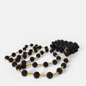 Close-up of handmade beaded strap with black bayberry beads and golden accents