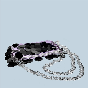 Close-up of sparkling black sequins and silver chain on a purple woven handbag