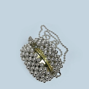 Detail of silver beaded spherical clutch with contrasting polished gold metal ring closure