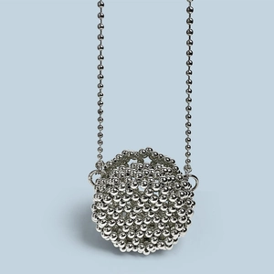 Macro shot of silver metal sphere bag with intricate hand-woven beaded texture