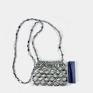 Macro shot of silver metal hollow-out mini bag with chain strap and size reference