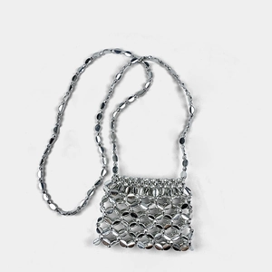 Macro detail of silver metallic hollow woven mini bag with shiny sequin chain strap
