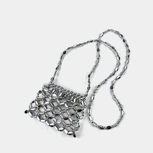 Macro shot of silver metal sequin handbag with handcrafted mesh links and long chain strap