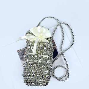 Detail of silver handmade beaded crossbody bag with a cream satin drawstring pouch